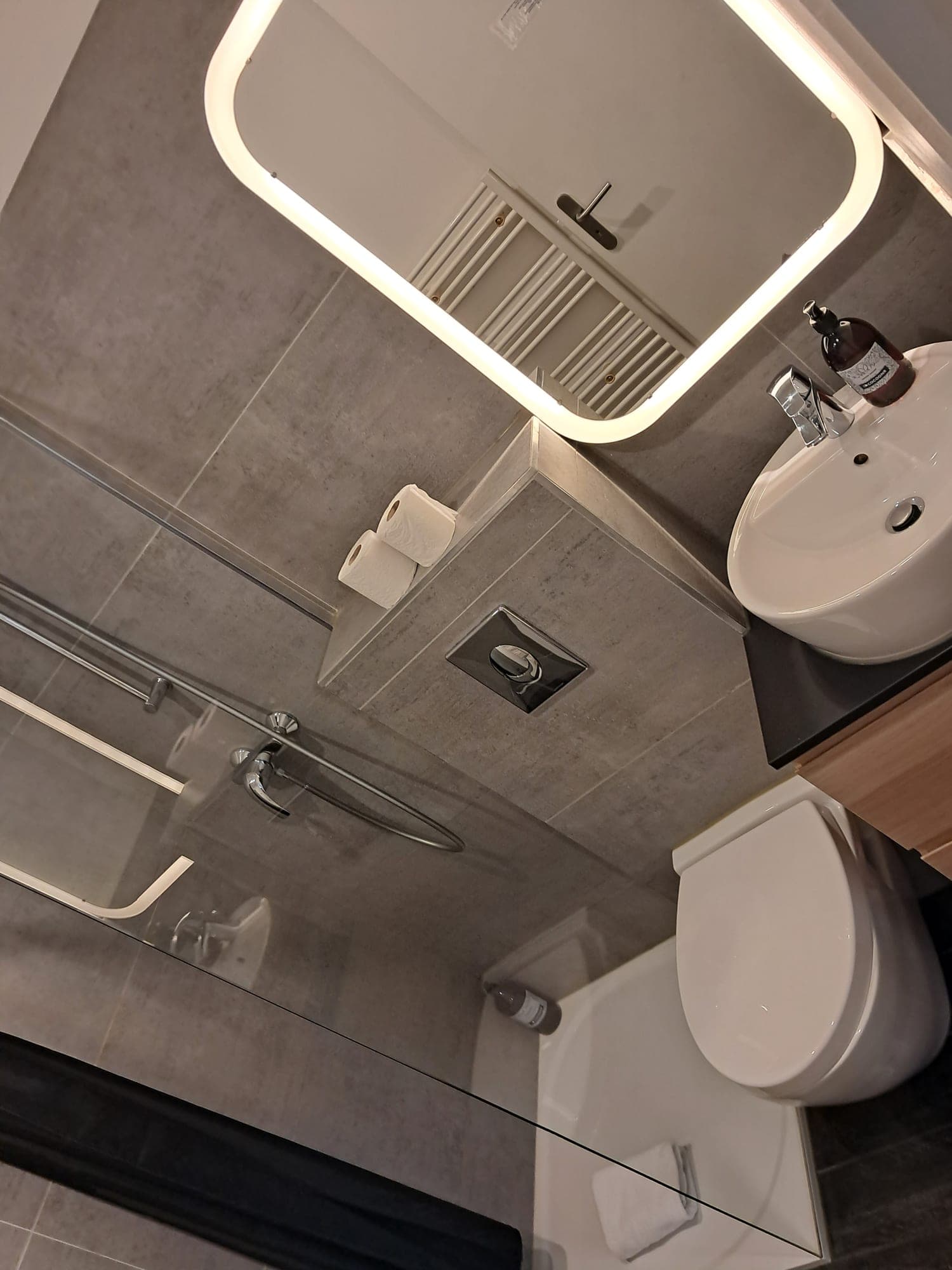 Grey shower room with backlit mirror, fittings and glazing streak-free