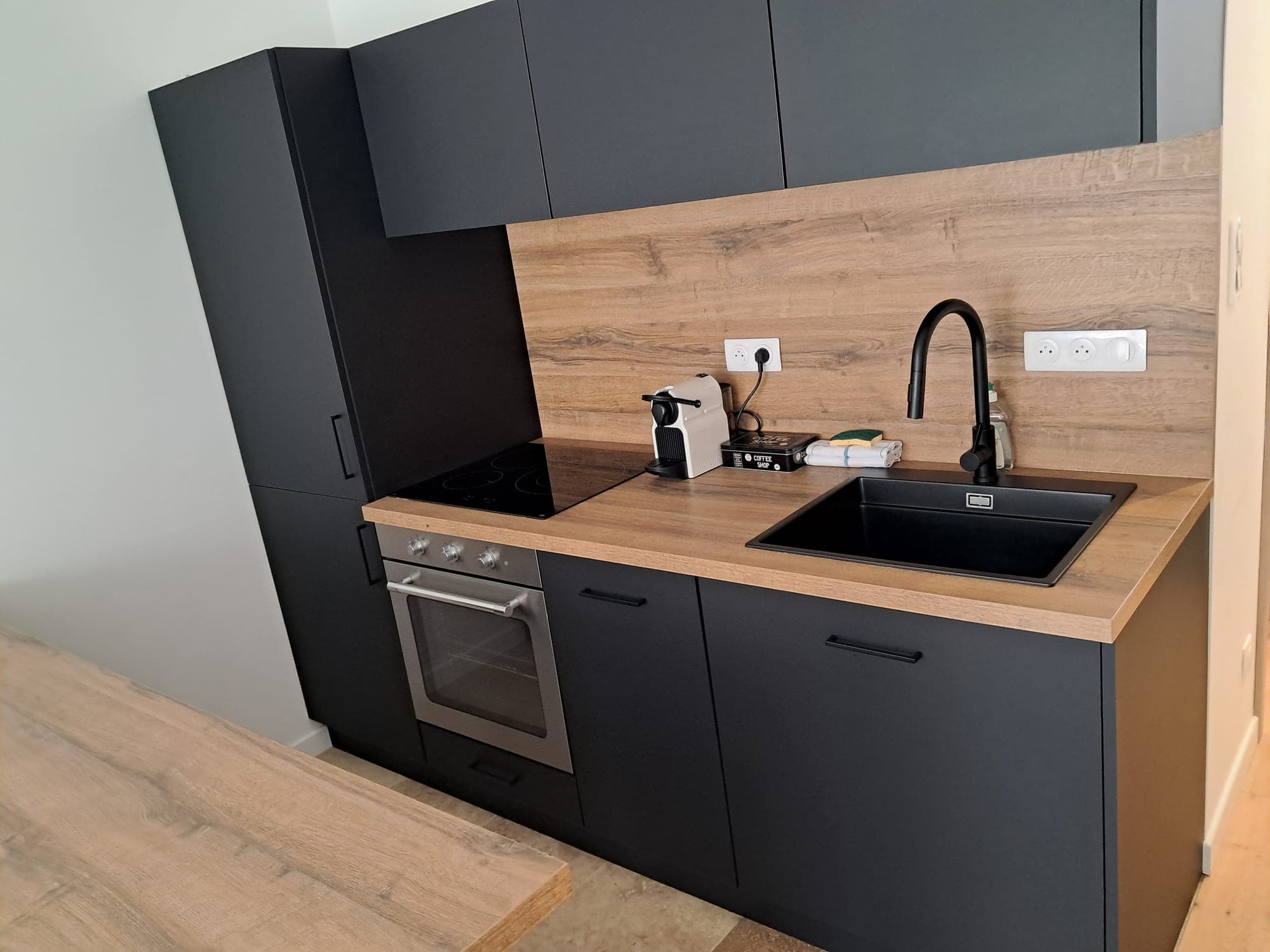 Matt black fitted kitchen with wooden worktop, maintained by Nailys Propreté