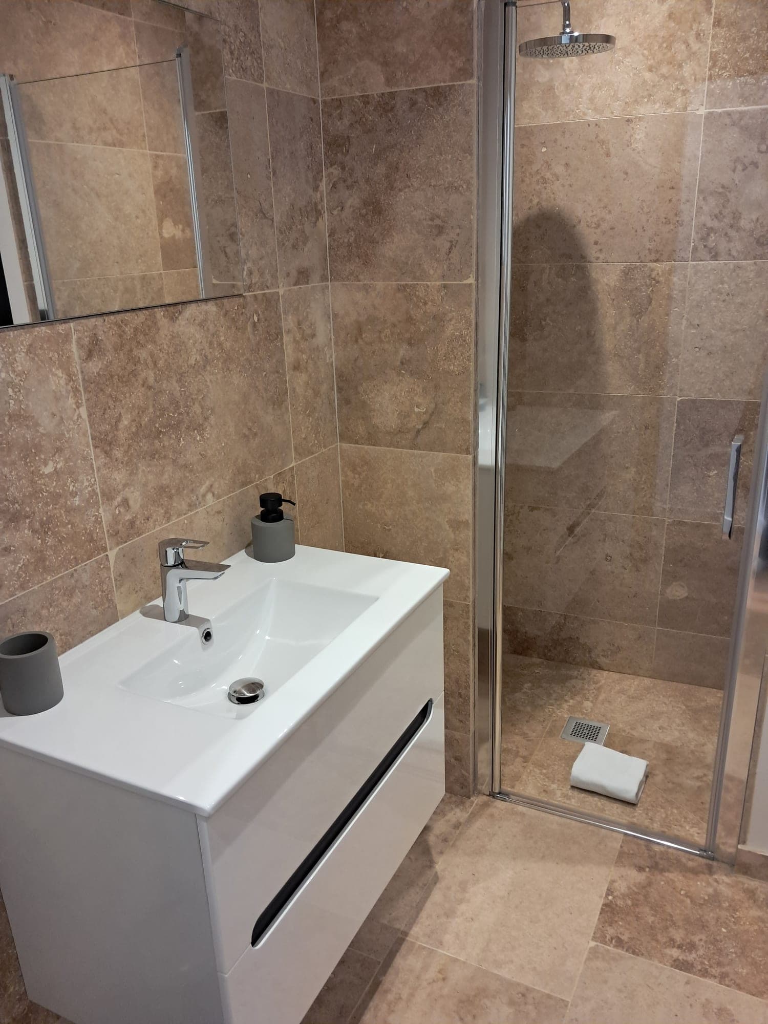 Travertine bathroom with walk-in shower, after servicing